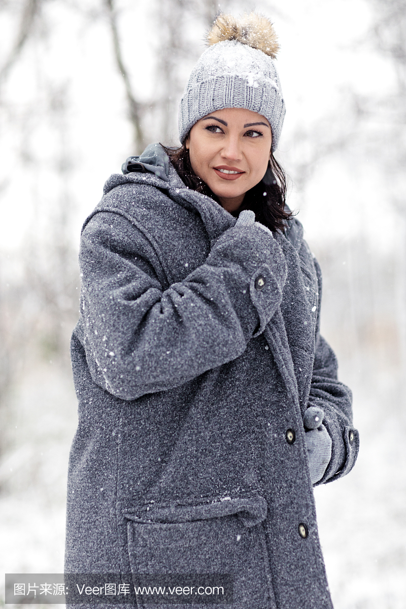 美丽的黑发女性运动女人穿着冬天的大衣在外面的雪